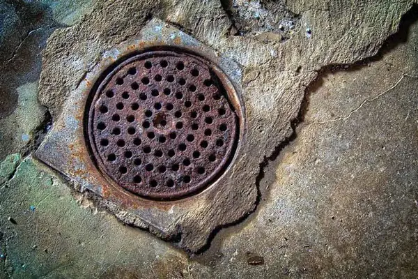 Rusted cast iron floor drain set in a basement slab