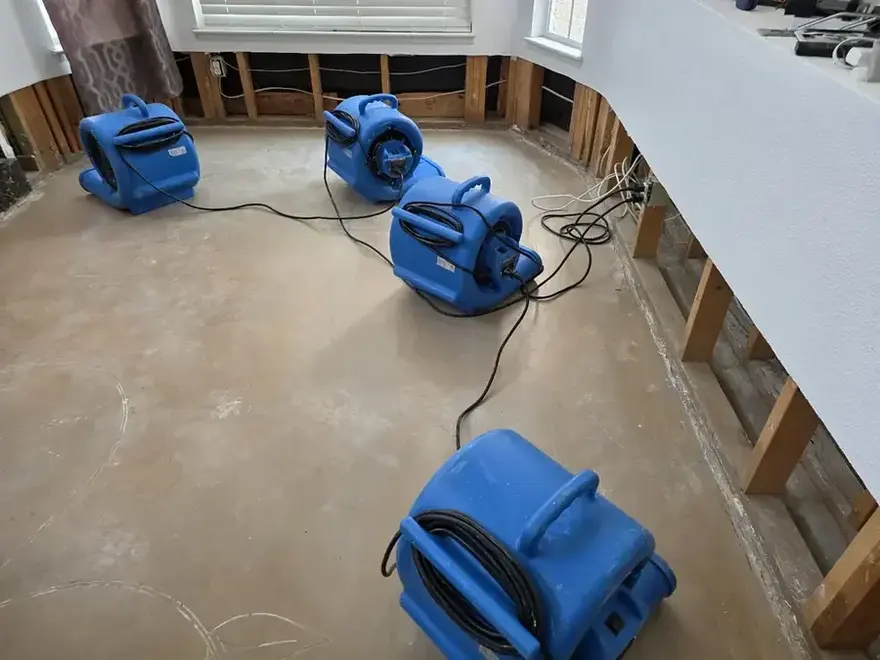 Air movers drying a lower-level room in a Sterling Heights home after the wet drywall was cut away